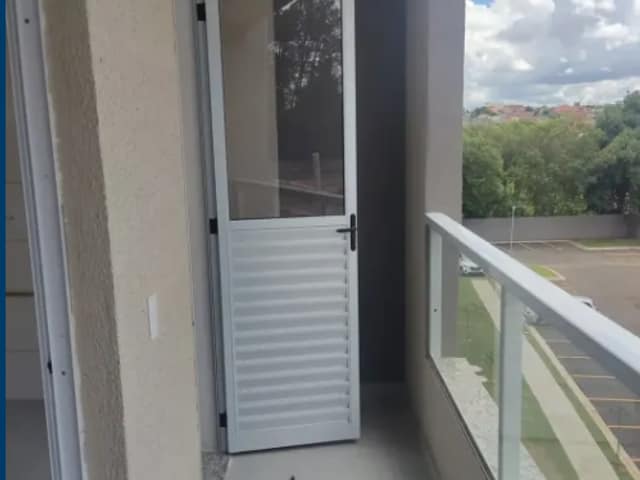 Varanda com guarda-corpo de vidro e piso de porcelanato