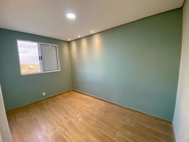Quarto com piso laminado e paredes pintadas de verde
